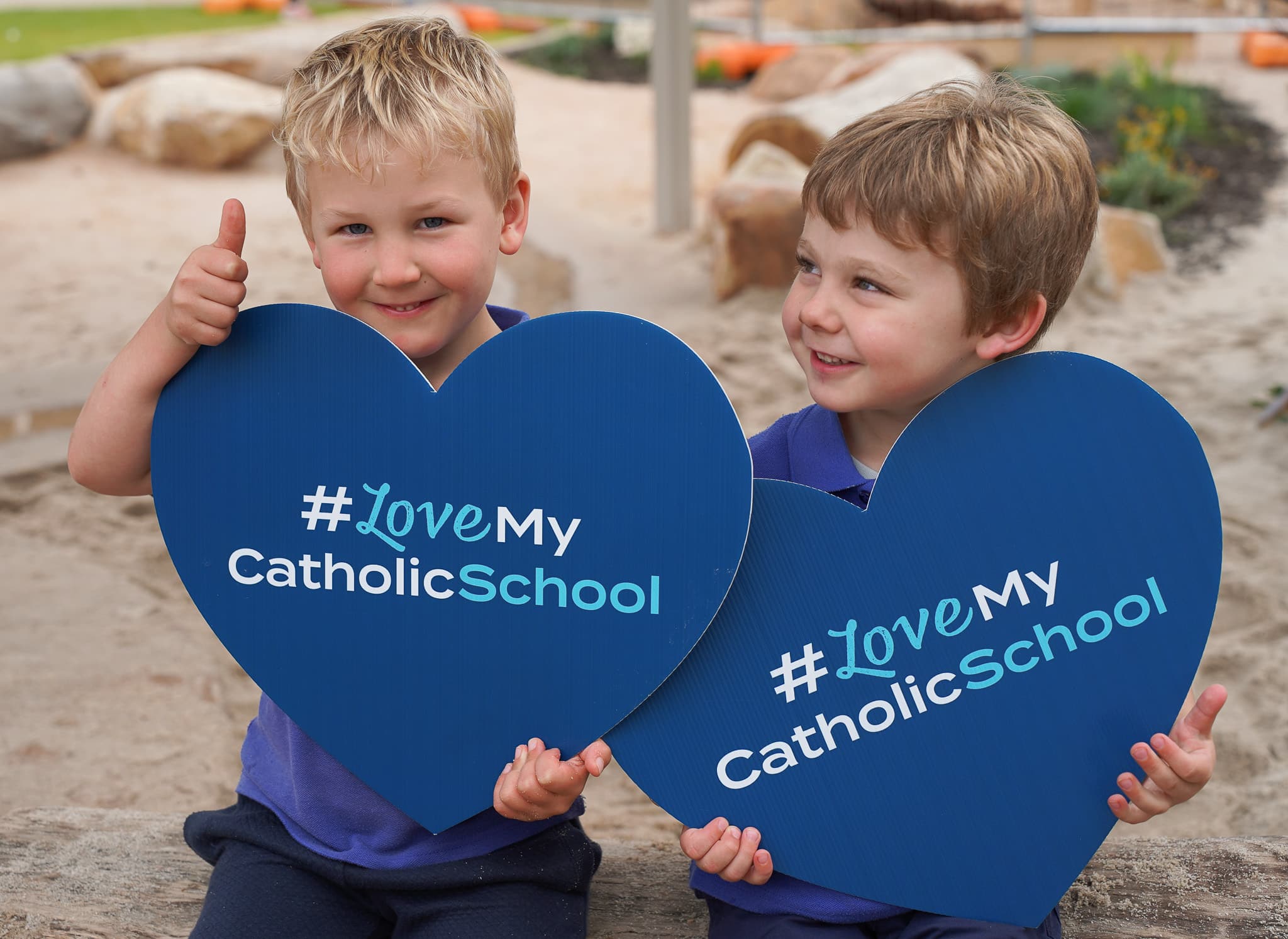 Junior Joey's students holding Love heart shaped Catholic School sign