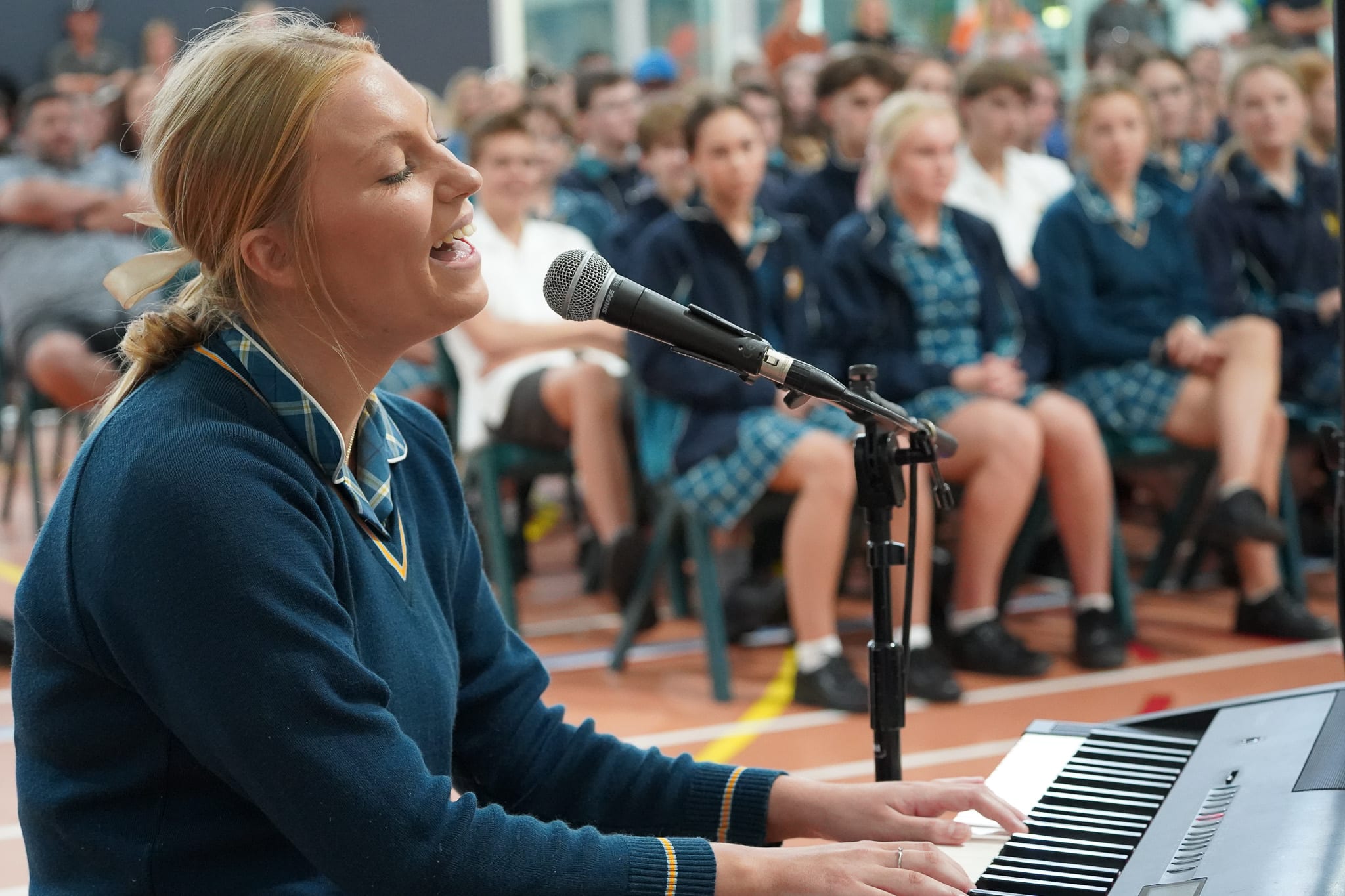 Student playing keyboard and singing at liturgy