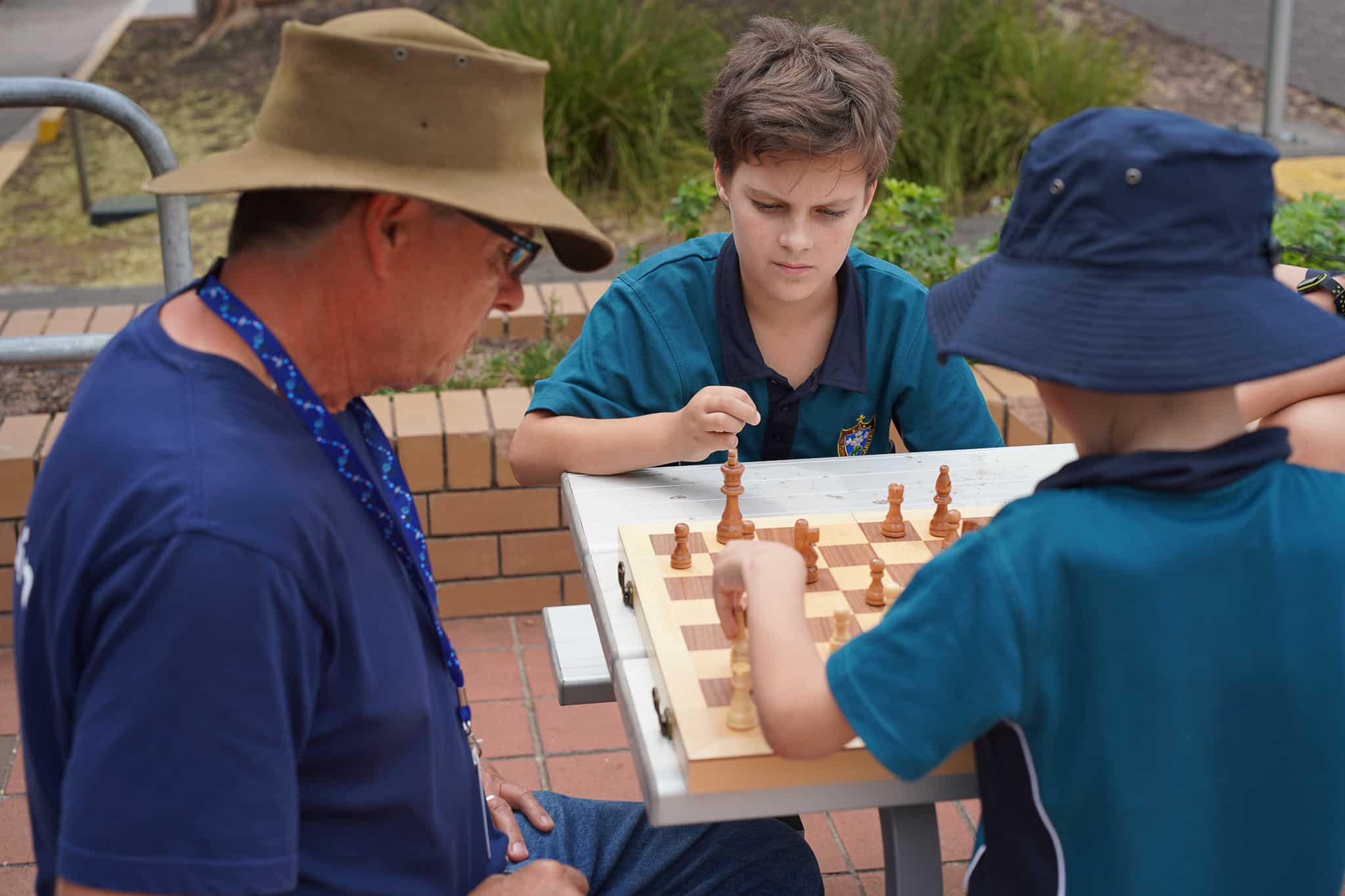 Students playing chess with School Chaplain